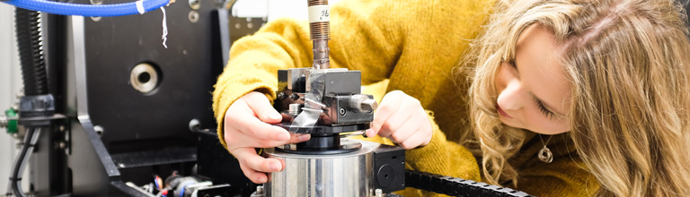 Researcher wearing yellow jumper adjusting machinery