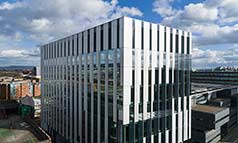 A grey, cuboid shaped building, made up of vertical sheets of glass.